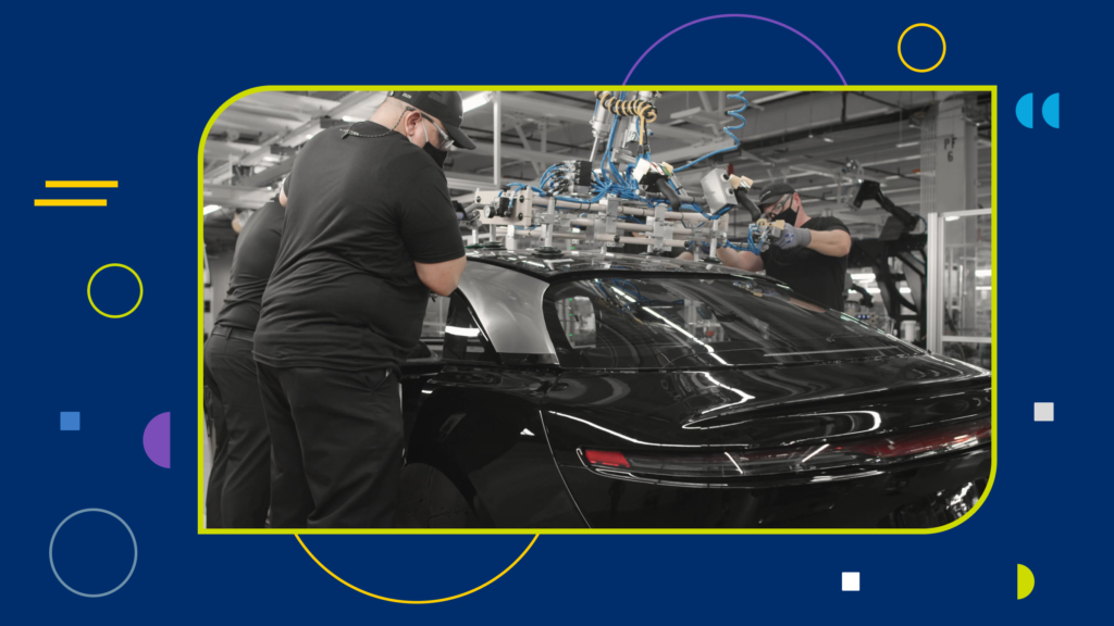 Two assembly workers using tools on an electric car.